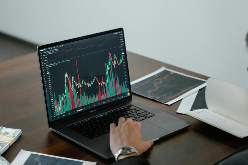 A person analyzing stock market data on a laptop with charts and graphs visible.